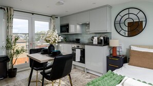 Een moderne hotelkamer met een kitchenette, een eethoek en een bed.