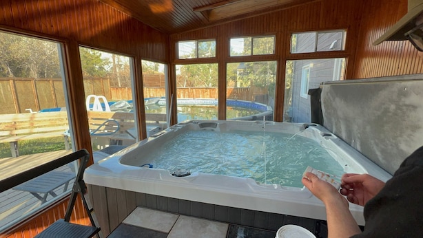 Un jacuzzi con muelle de madera y vista a un patio trasero con piscina.