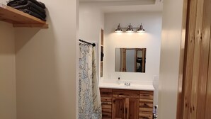A bathroom with a wooden vanity, a sink, and a mirror. There is a shower curtain with a map pattern.