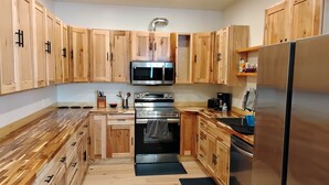 A modern kitchen with wooden cabinets, stainless steel appliances, and a black countertop.