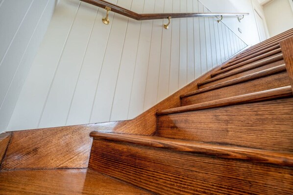 Una escalera de madera con barandilla de metal y pasamanos de latón.