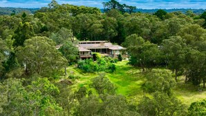 A house surrounded by dense greenery, with a clear view of the surrounding forest. - Tranquil Cottage with Valley & Hills Views (Wonga Park)