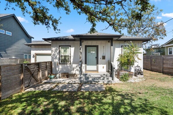 A residential house with a front porch, a garage, and a fenced yard. - Spacious 3BR w Parking Pet Friendly (Austin)