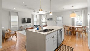 A modern kitchen with a central island, wooden dining table, and pendant lighting. - Spacious 3BR w Parking Pet Friendly (Austin)