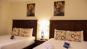 A hotel room with two beds, each with patterned pillows and a nightstand with a lamp.