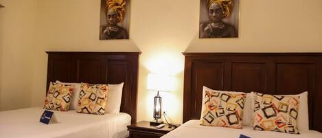 A hotel room with two beds, each with patterned pillows and a nightstand with a lamp.