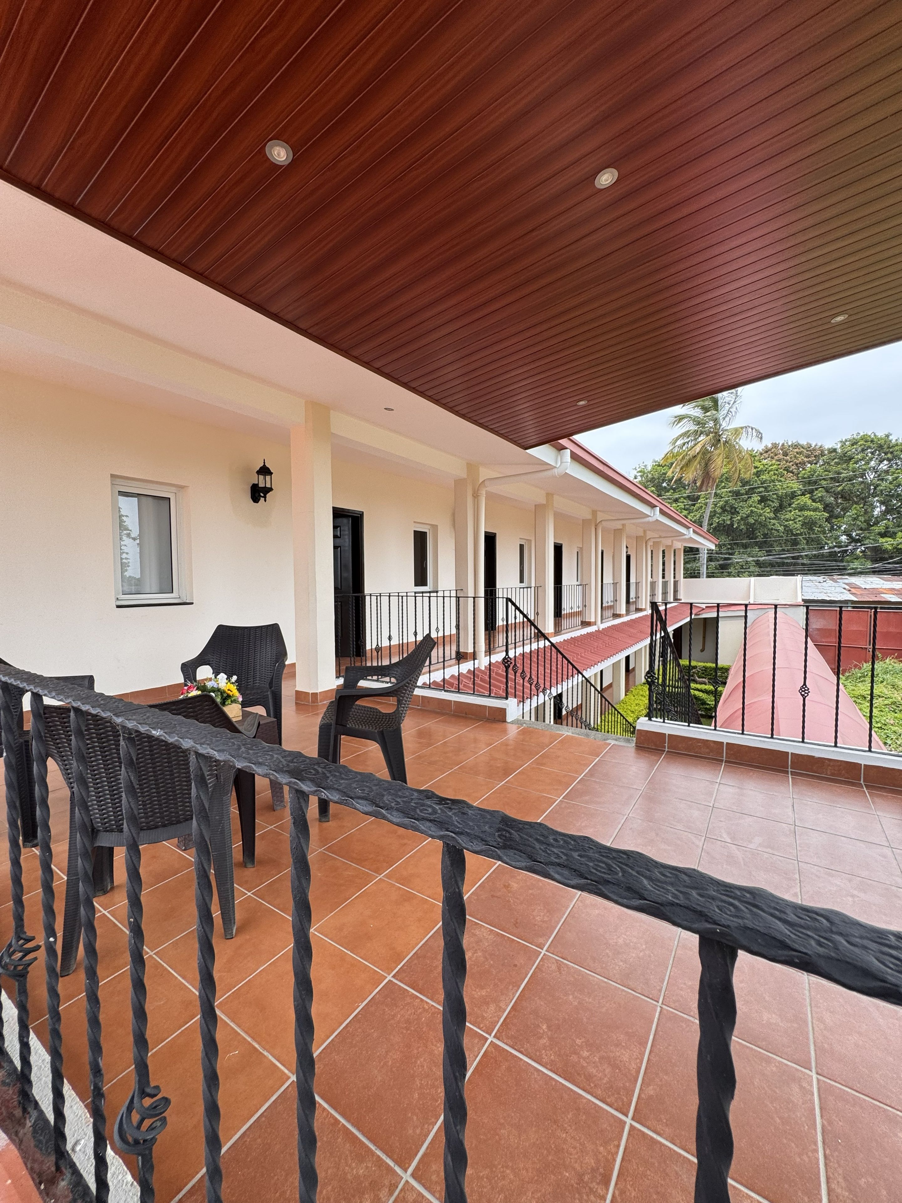 Un espacio al aire libre techado con suelo de baldosas, techo de madera y barandilla.
