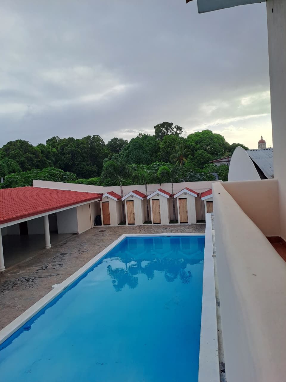 Una piscina con un edificio de techo rojo al fondo.