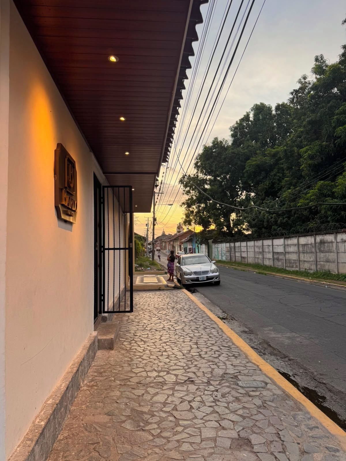 Vista de la calle con un edificio que tiene un paseo empedrado y una reja de metal.