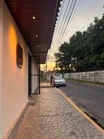 Vista de la calle con un edificio que tiene un paseo empedrado y una reja de metal.