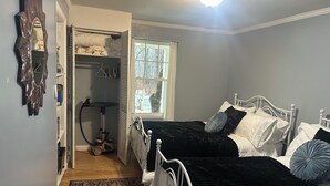 Un dormitorio con dos camas, una ventana, un radiador y un armario.