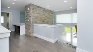 A modern kitchen with a stone accent wall, recessed ceiling lights, and a view to the outdoors.