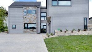 A modern two-story house with a stone facade, large windows, and a well-maintained lawn.