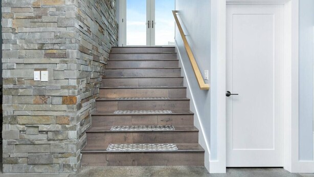 A staircase with stone walls, wooden steps, and a white door.