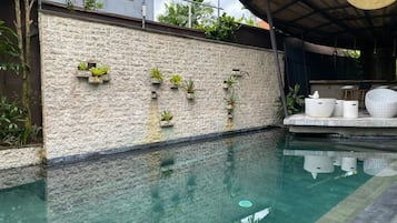 Una piscina al aire libre, sillones reclinables de piscina