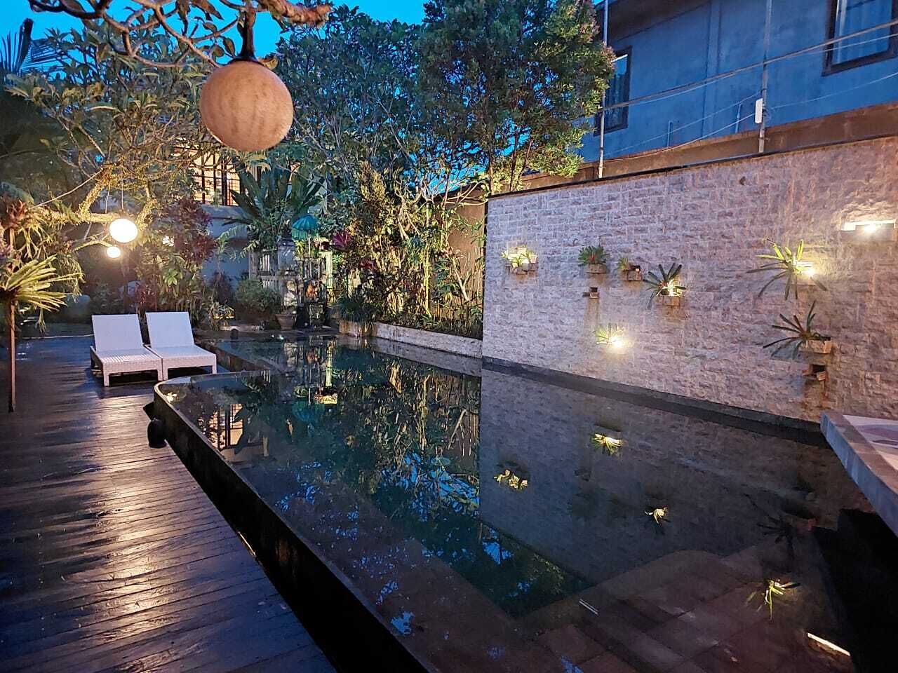 A serene outdoor pool area with lounge chairs and a stone wall.