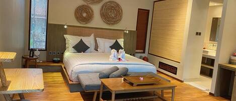 Una habitación de hotel moderna con una cama grande, piso de madera, un escritorio y una mesita.