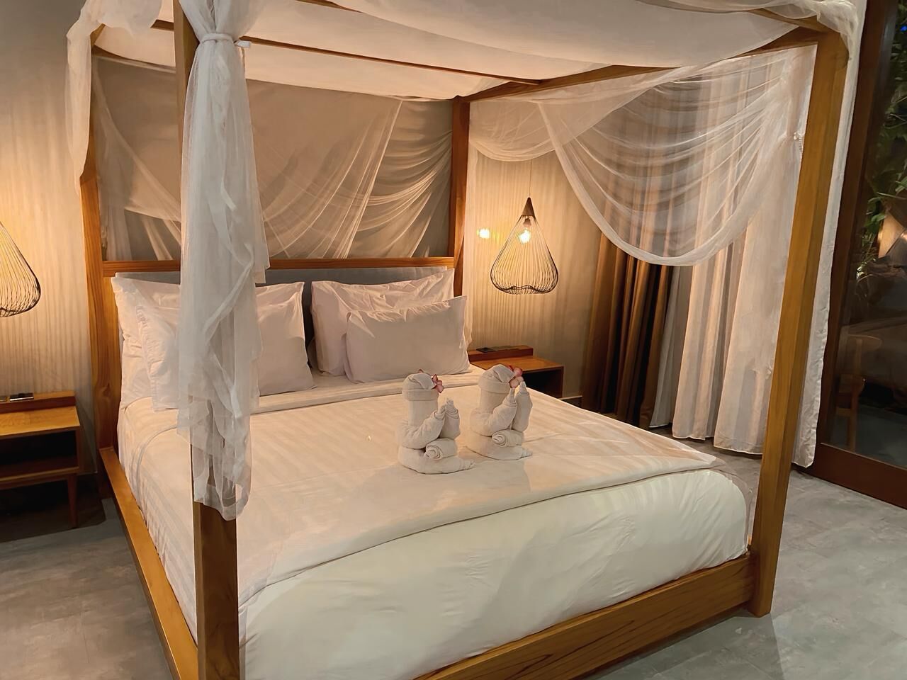 A four-poster bed with white linens and two towels on the bed.