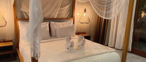 A four-poster bed with white linens and two towels on the bed.