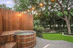A wooden spa area with a hot tub, surrounded by a well-maintained lawn and trees. - South Lamar Luxe Creekside Hot Tub (Austin)
