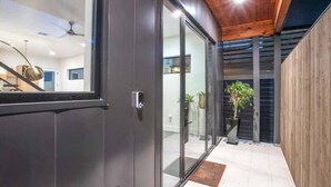 A modern interior with a sliding glass door leading to a balcony with potted plants. - South Lamar Luxe Creekside Hot Tub (Austin)