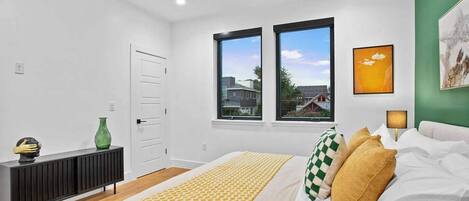 A modern bedroom with a bed, two windows, a ceiling fan, a bedside table, and a green vase.