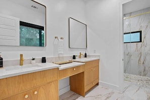 A modern bathroom with two sinks, wooden cabinets, and a large mirror.