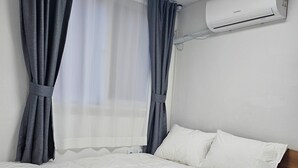 A bedroom with a bed, curtains, an air conditioning unit, and a window. - Daldal Masil (Mokpo)