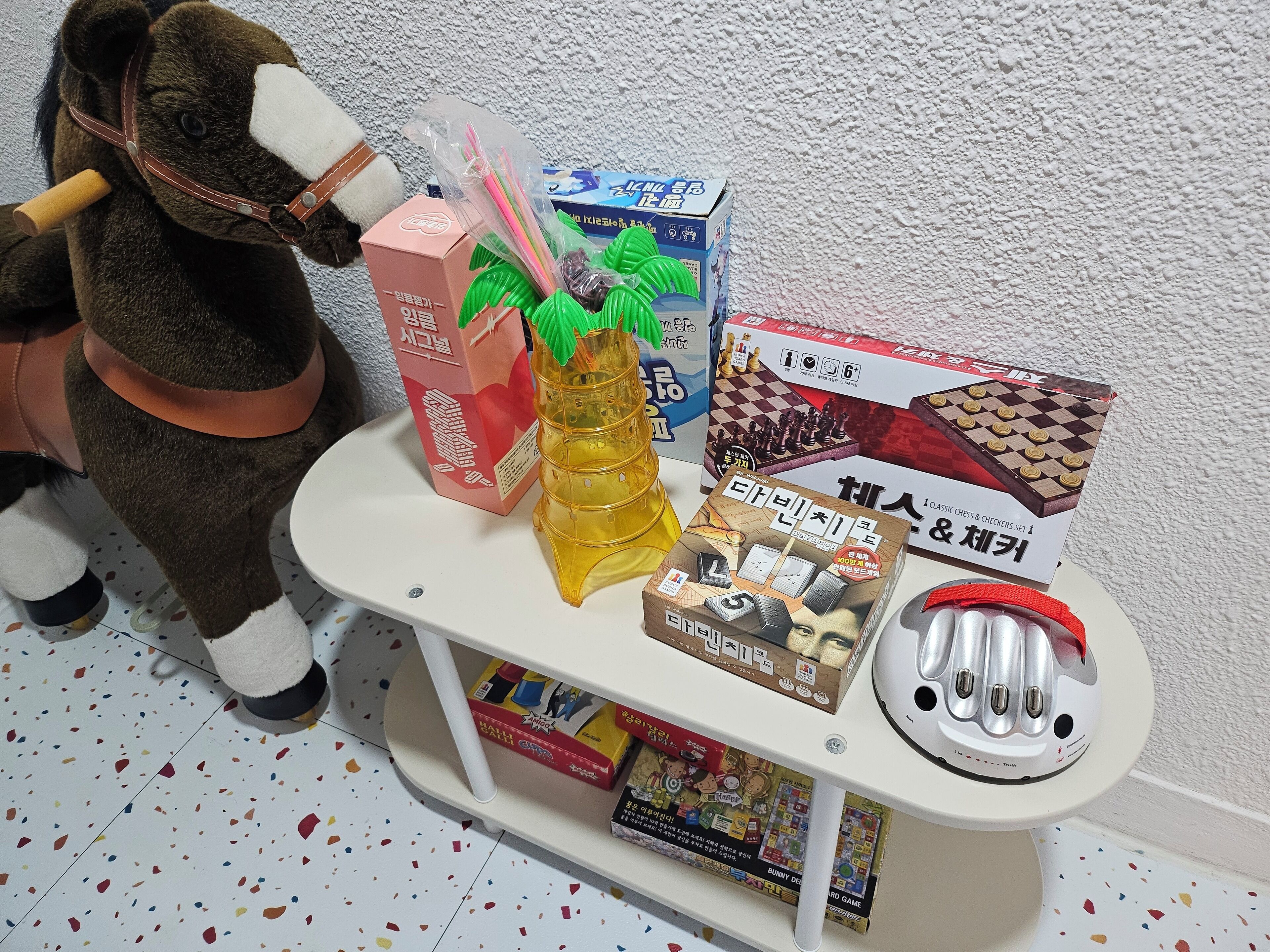 Uma pequena mesa com vários jogos de tabuleiro, um brinquedo de pelúcia e algumas caixas.