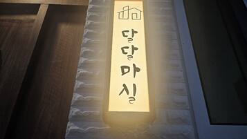 Un panneau lumineux avec des caractères japonais sur un mur à texture.