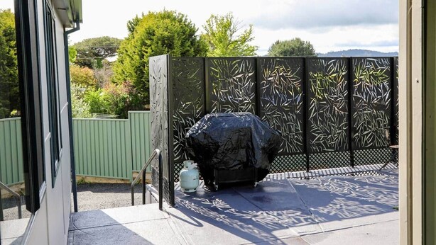 A patio with a decorative fence, a covered object, and a small table. - Modern Home - 2 min To CBD - Near Lakes & Forests (Oberon)