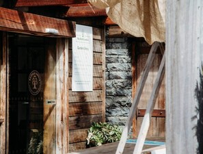 A rustic wooden building with a stone wall and a sign for 'Maxfield Garden' indicating garden entry.