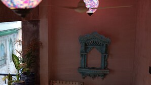 A corner room with a ceiling fan, a decorative mirror, and potted plants. - Fort View (Jodhpur)