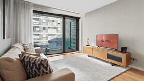 Uma sala de estar moderna com um sofá, uma televisão de tela plana e um móvel de TV de madeira.
