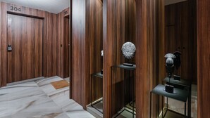 Interior de elevador moderno com painéis de madeira e portas numeradas, 304 e 305.