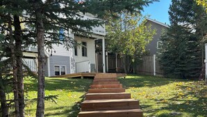 A set of wooden and stone steps leading up to a house with a white exterior, surrounded by trees and a grassy yard. - Hinton Mountain House (Hinton)