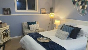 A neatly made bed with a tray, a chair with a cushion, a bedside table, and a lamp. - Hinton Mountain House (Hinton)