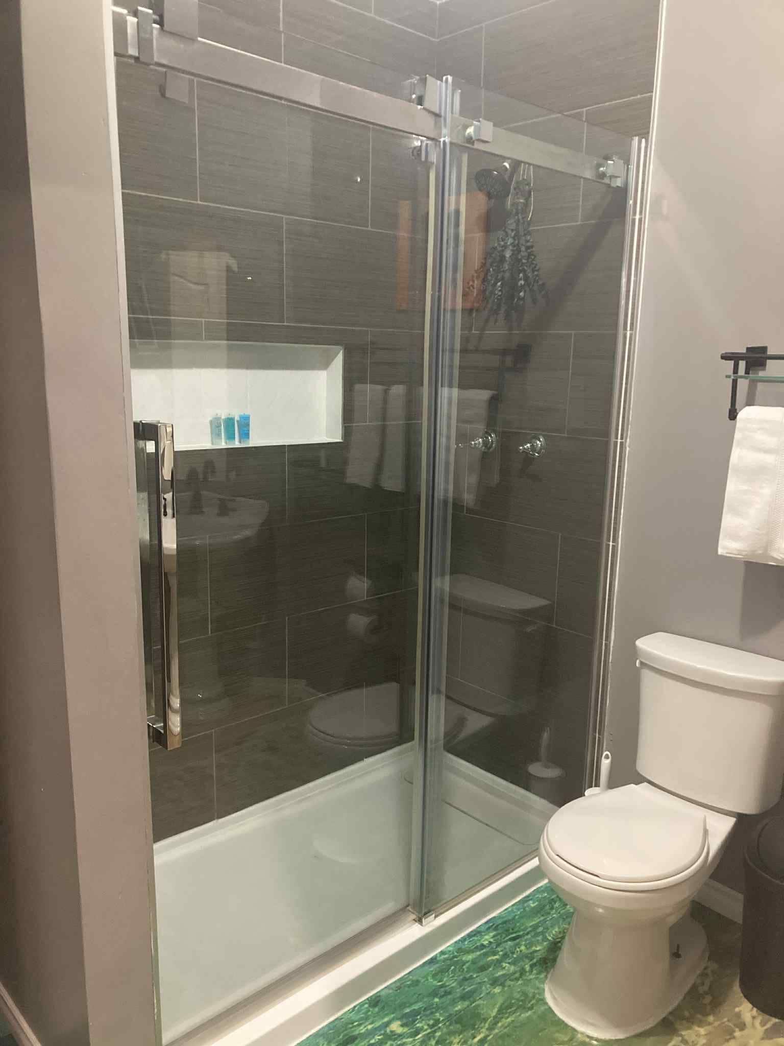 A modern bathroom with a glass-enclosed shower, a toilet, and a white sink.