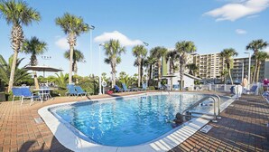 Una piscina con lettini e palme.