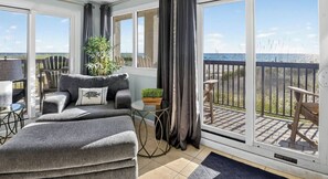 A balcony with a view of the sea, a sofa, a small table, and a potted plant.