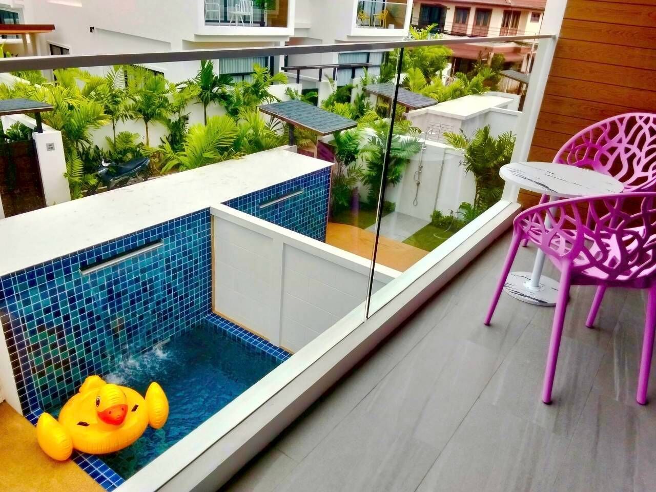 Een balkon met een klein zwembad, een roze stoel en een gele badeend.