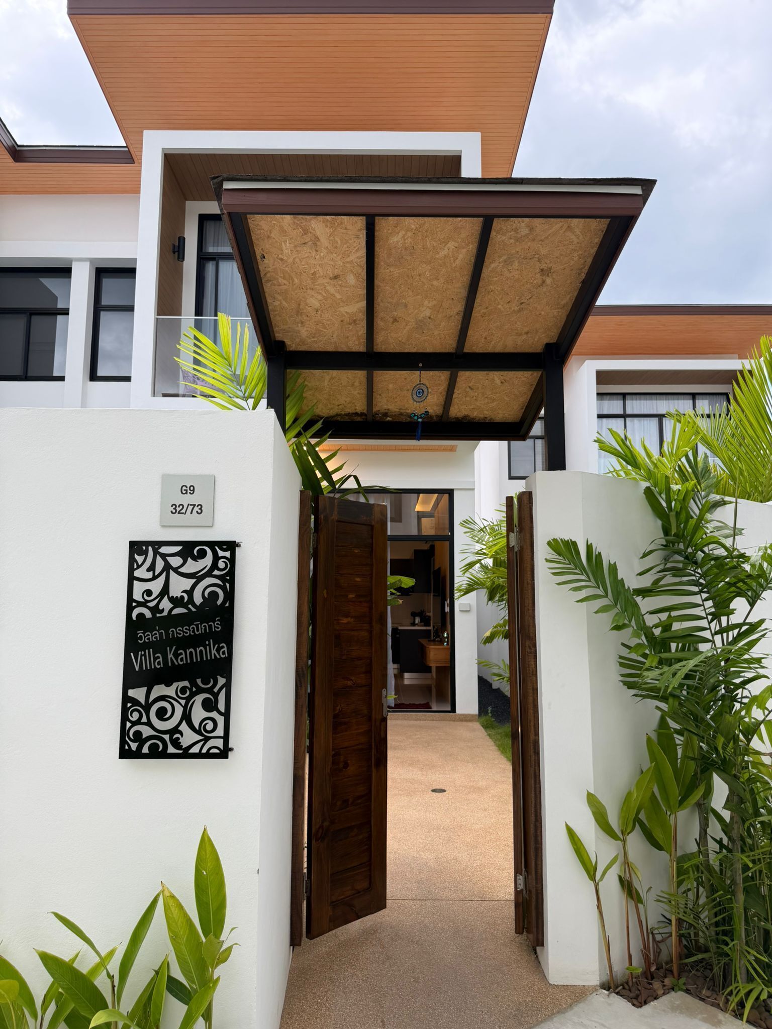 A modern villa with a covered entrance, a sign indicating room number G9, and a view into the interior.