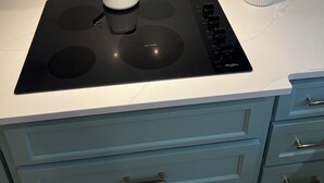 Une cuisine dotée d’une plaque de cuisson à induction noire, d’une bouilloire blanche et d’un porte-ustensiles.