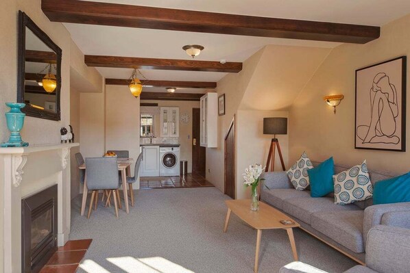 Ein Wohnzimmer mit Kamin, einer Couch, einem Couchtisch und einer Küche im Hintergrund.