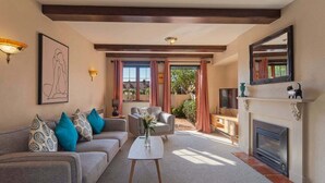 A living room with a sofa, armchairs, a coffee table, a fireplace, and a large window with curtains.