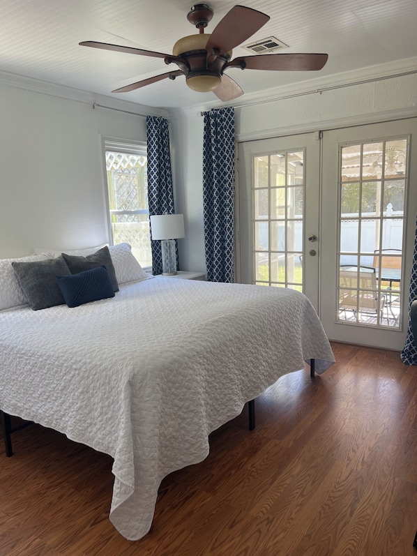 A bedroom with a large bed, a ceiling fan, and a view through a glass door. - Home 5 minutes near Kemah Boardwalk - Dog Friendly - Yard & Fenced-in Patio (Bacliff)