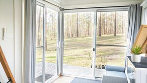 A room with a sliding glass door leading to a deck, a small table with a plant, and a bench.