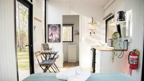 A bedroom with a bed, a desk, and a view of the outdoors.