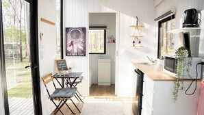 A compact kitchen with a wooden countertop, a sink, and a microwave. There is a small dining area with a table and chairs.