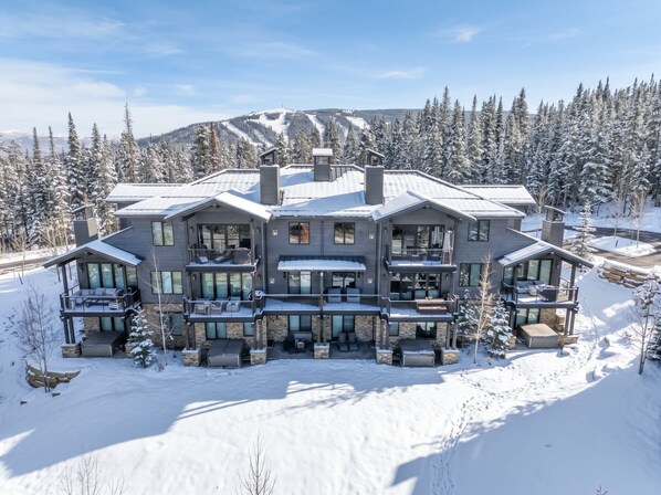 A large, multi-story building with a symmetrical facade, multiple balconies, and a snow-covered landscape.